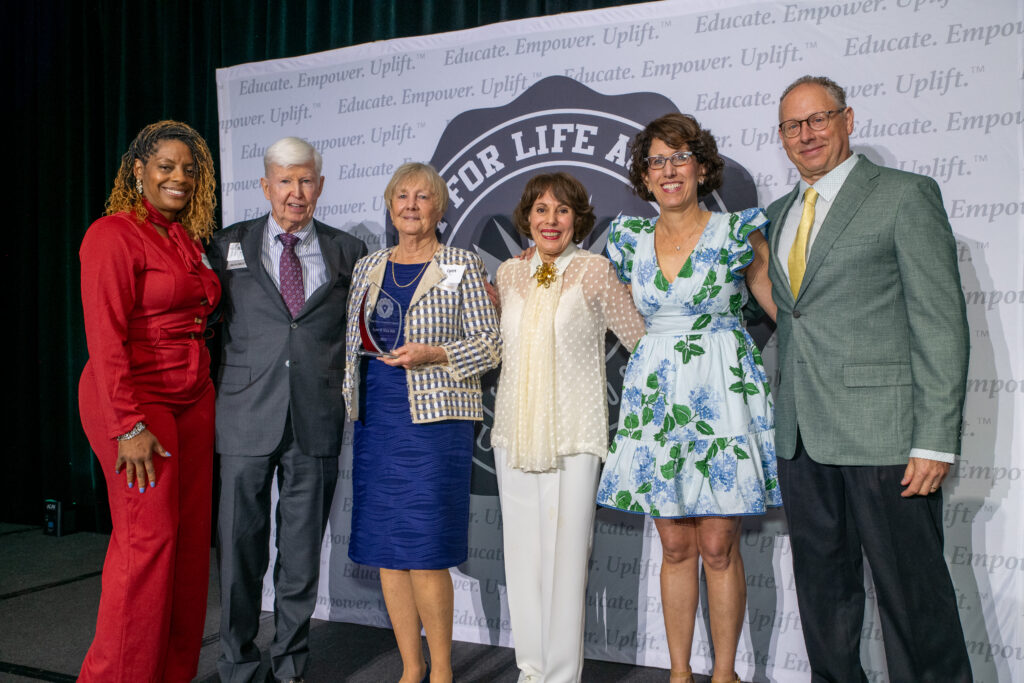 six people lined up on stage, two of them receiving an award